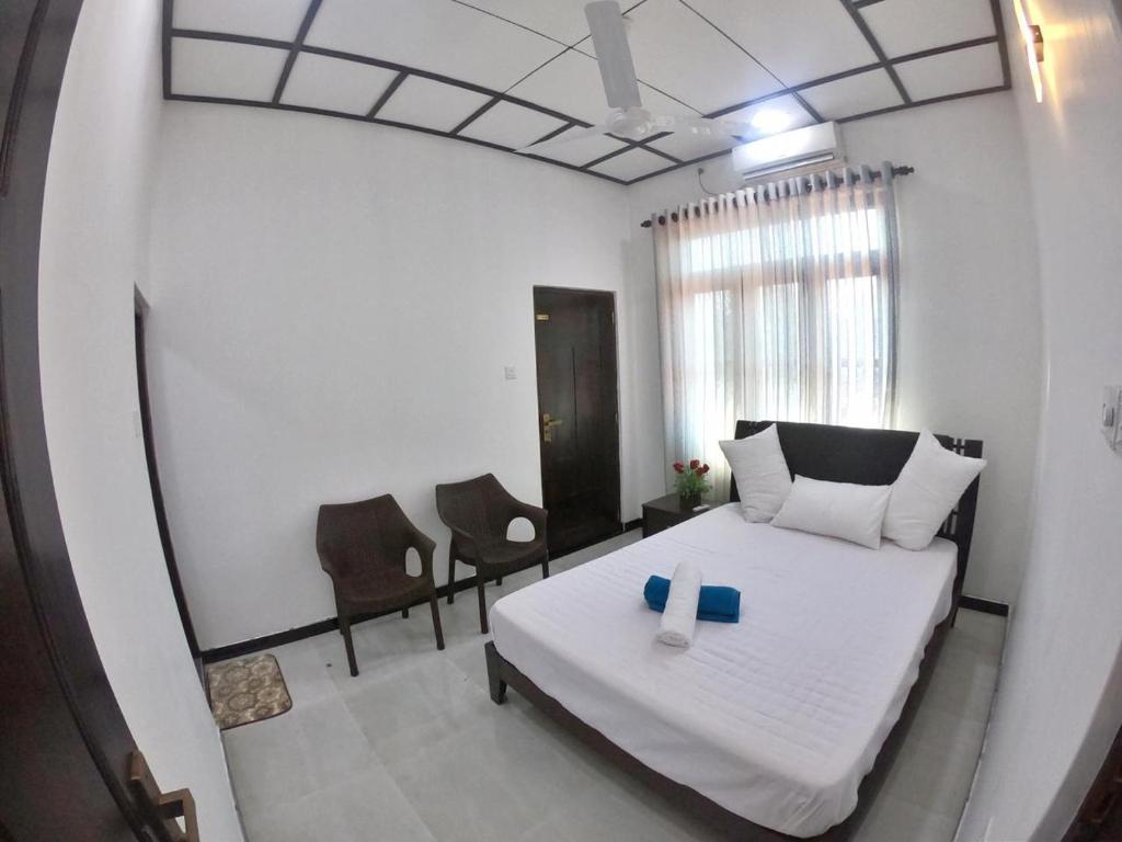 a bedroom with a bed and two chairs in it at Juliya Guest House in Negombo