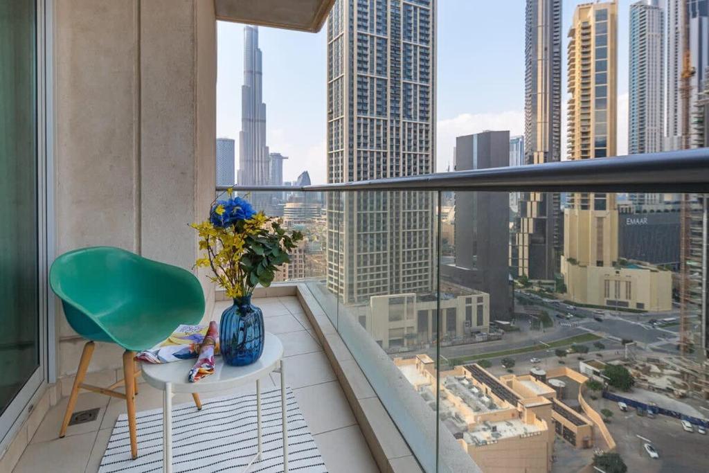 a balcony with a green chair and a vase of flowers at Frank Porter - Burj Views in Dubai