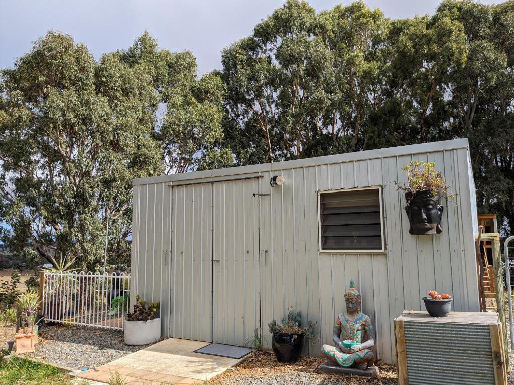 a small shed with a statue next to it at The Buddha Shed in Hindmarsh Valley