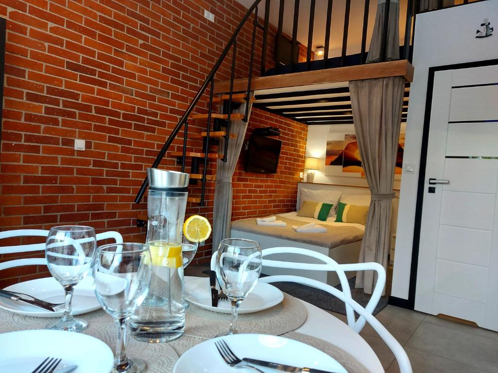 een tafel met wijnglazen en een slaapkamer bij Apartament typu studio Morski Sen-centrum in Mielno