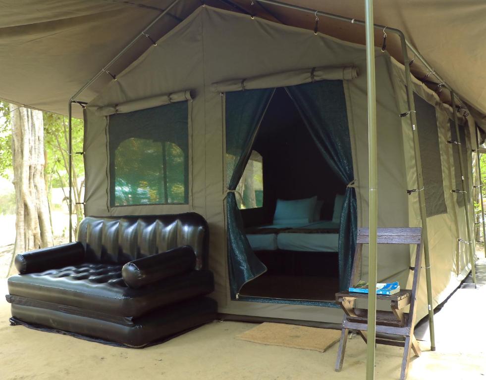 マータラにあるLeopard Glamping - Luxury Mobile Campsite in Yala & Kumanaのベッド1台とテント内のソファが備わる客室です。