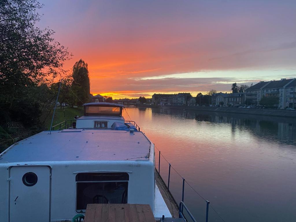 łódź zacumowana na rzece o zachodzie słońca w obiekcie Péniche à 25 mn de Paris w mieście Creil