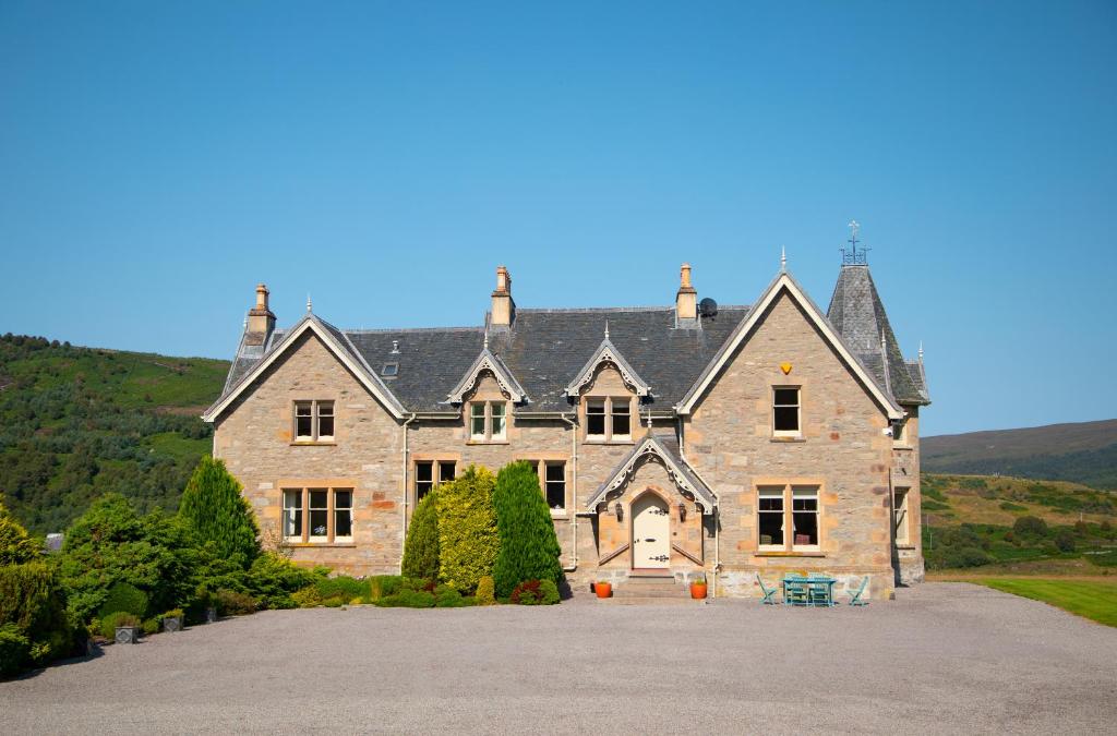 a large stone house with a large driveway at Inveroykel Lodge at Rosehall in Rosehall