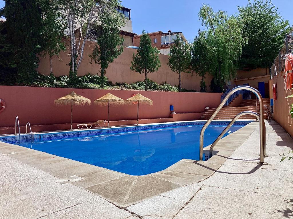 uma piscina com guarda-sóis ao lado de um edifício em CASA LOS ABETOS cerca de la Alhambra y Sierra Nevada em Cenes de la Vega