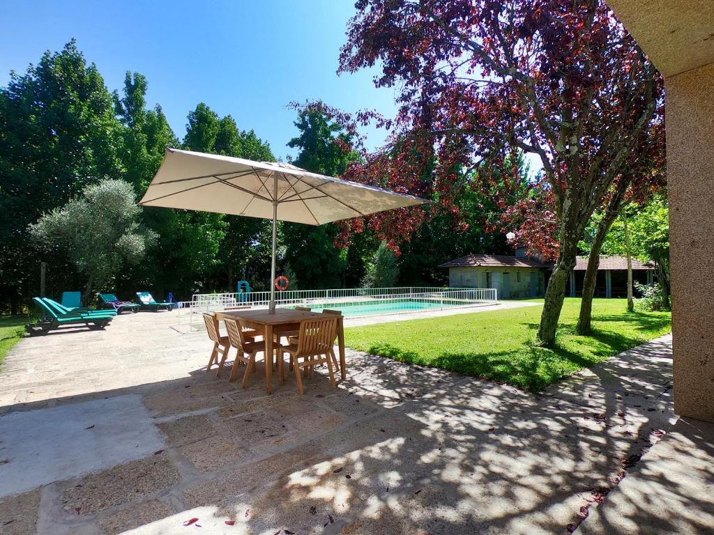 a table and chairs with an umbrella next to a pool at Jardim da Guida in Abragão