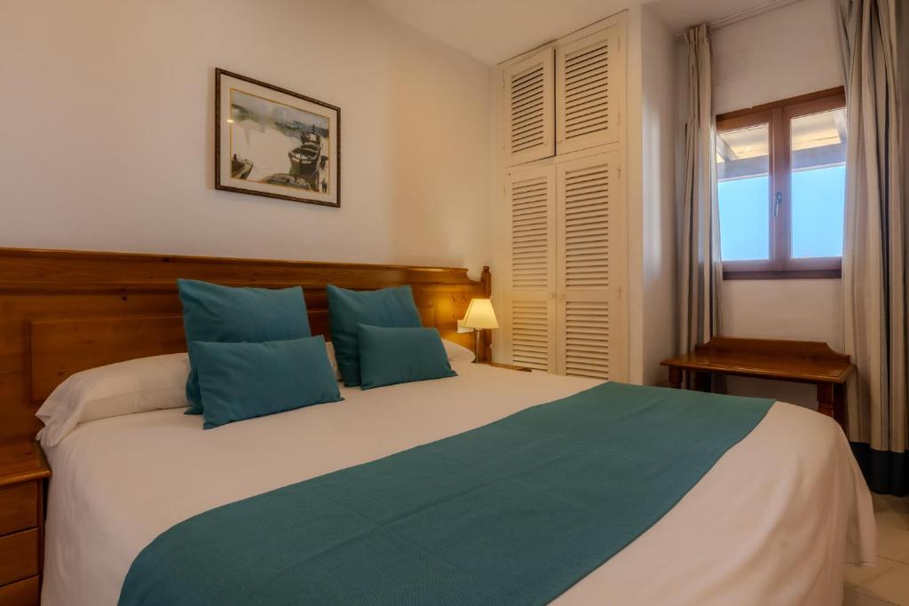 - une chambre avec un grand lit et des oreillers bleus dans l'établissement Hotel Club Sunway Punta Prima, à Es Pujols