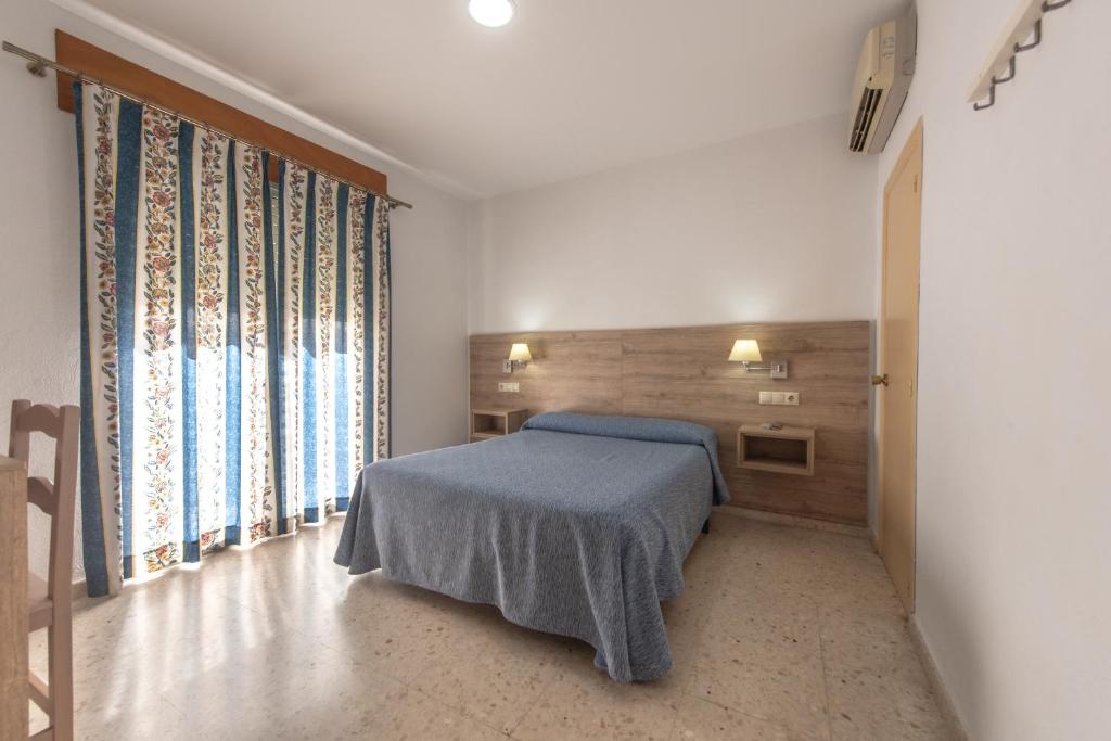 a bedroom with a bed and a large window at Hotel San Andres in Jerez de la Frontera