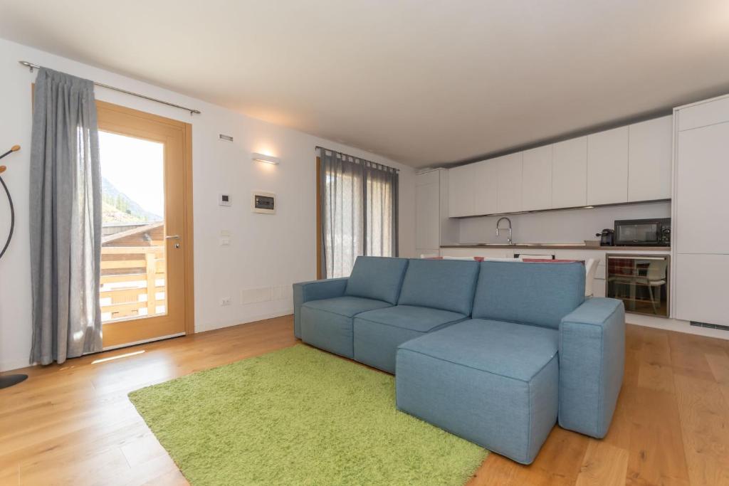 a living room with a blue couch and a kitchen at La Casa di Sofia in Alleghe