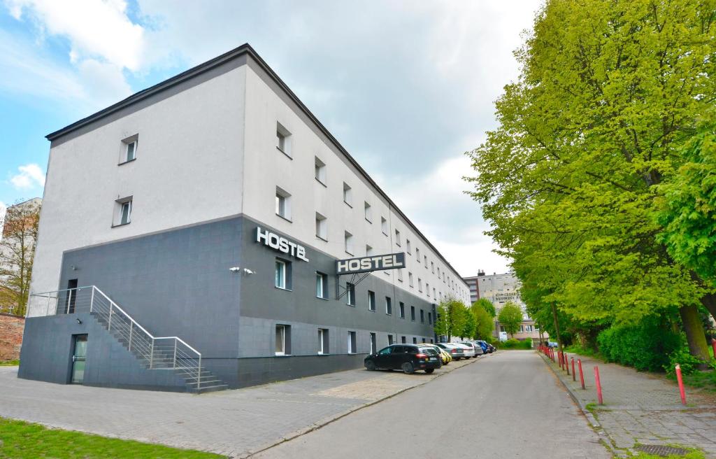 un gran edificio blanco con un coche estacionado al lado en Twój Hostel Klimczoka 7, en Katowice