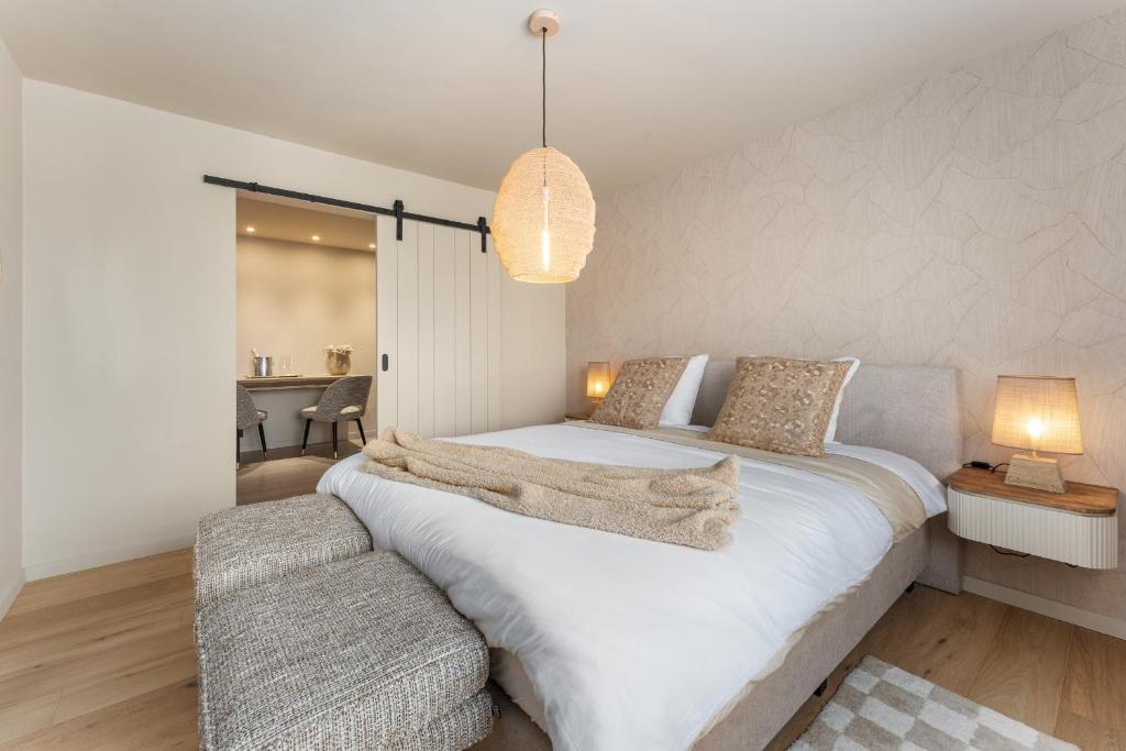 ein Schlafzimmer mit einem großen weißen Bett und einem Stuhl in der Unterkunft Maison Noomi in Knokke-Heist