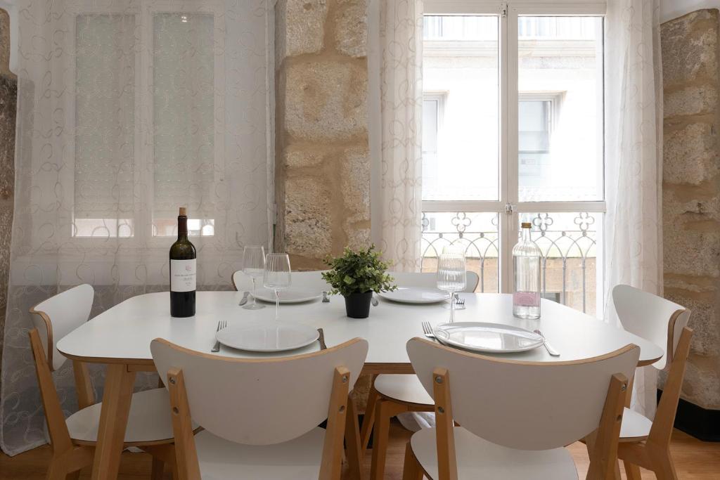 un comedor blanco con una mesa blanca y una botella de vino en Centro Histórico - Checkin automático en Vigo