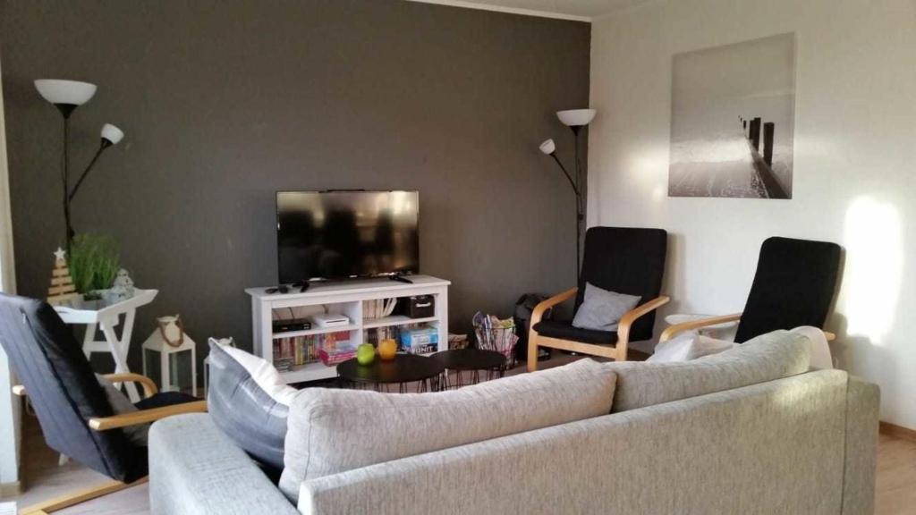 ein Wohnzimmer mit einem Sofa, Stühlen und einem TV in der Unterkunft Haus Seewind in Wesselburen
