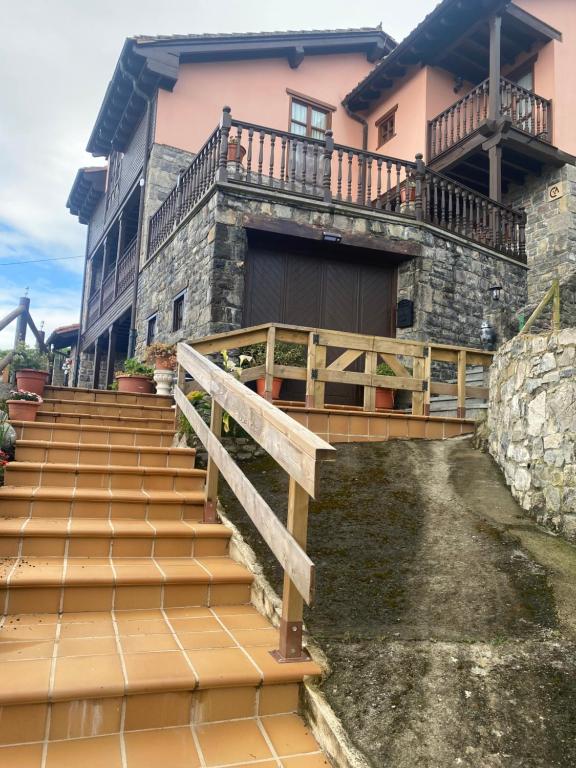 a house with a wooden staircase in front of a house at Casa Rural La Xana in Piloña
