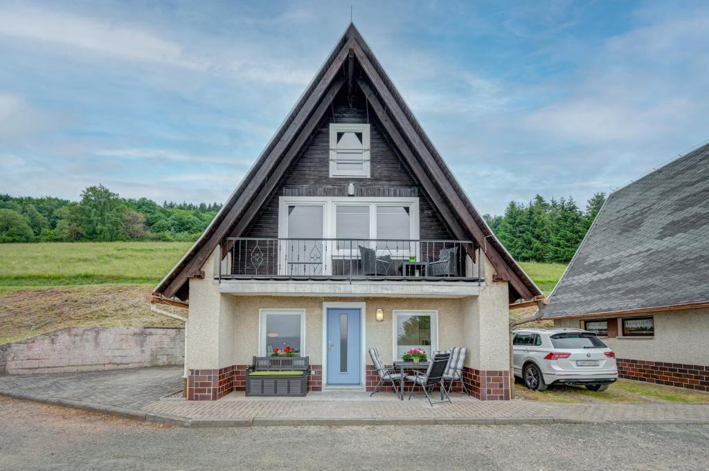 uma casa com um telhado de gambrel com uma varanda em Ferienhäuser Hohe Klinge em Brotterode