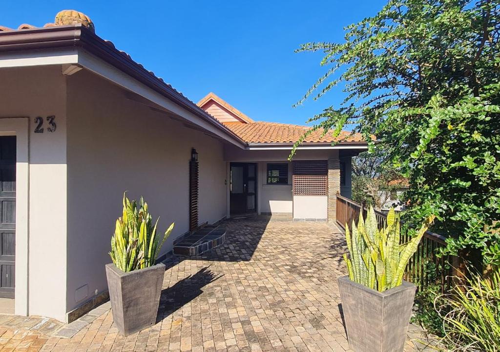 a house with two potted plants in front of it at Zimbali KJ01 4 Bedroom Home in Ballito