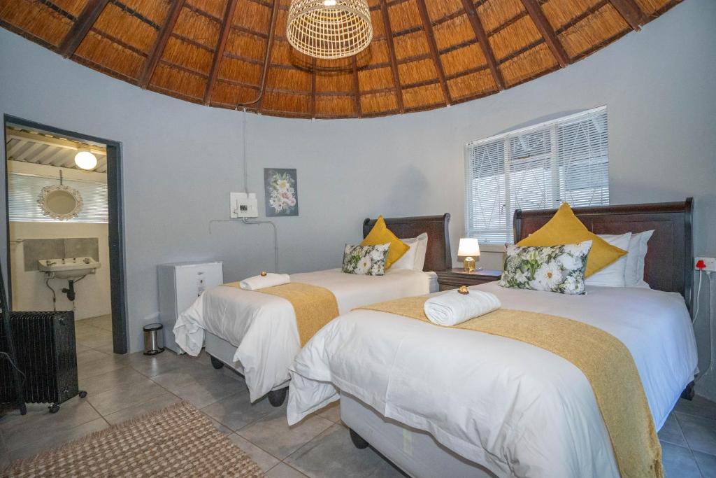 a bedroom with two beds with white sheets and yellow pillows at 19th Hut in Pretoria