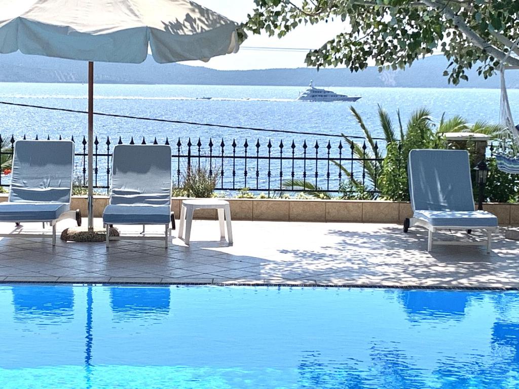 Mourterón的住宿－Beach villa Alonissos for 4 people，游泳池旁的两把椅子和一把遮阳伞