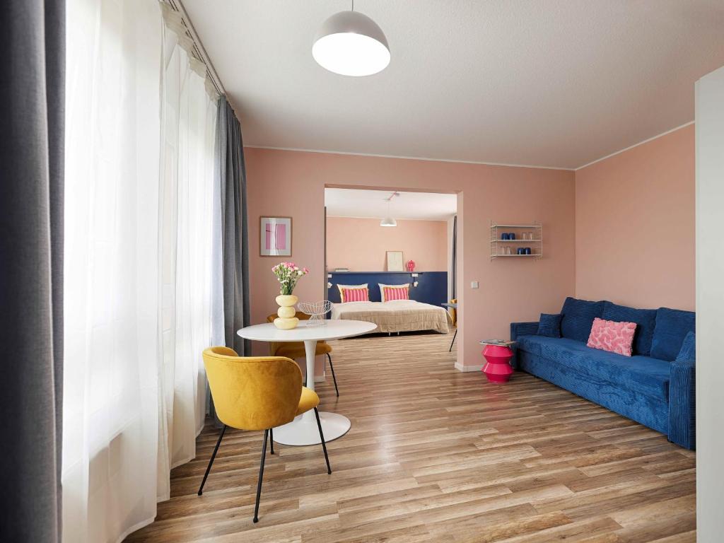 MaxAparthotel by homekeepers في فورث: غرفة معيشة مع طاولة وأريكة زرقاء