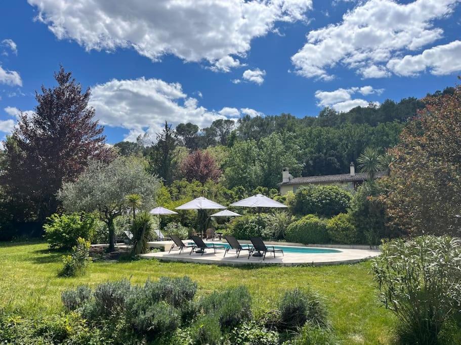 - une piscine avec 2 chaises et des parasols dans une cour dans l'établissement Maison Moutas, au Thoronet