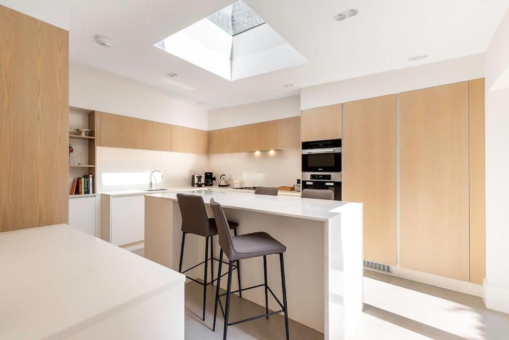 a kitchen with a white counter and stools at Urban Living - 2Bed 2Bath in South Kensington in London