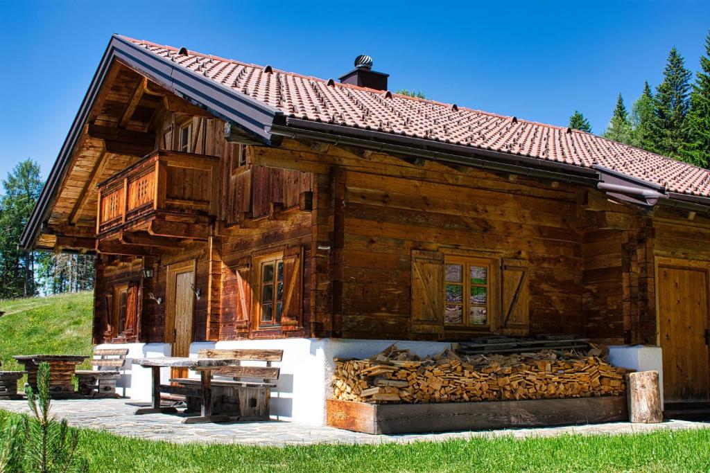 ein Holzhaus mit einem Holzstapel im Freien in der Unterkunft Bergquellenhütte in Assling