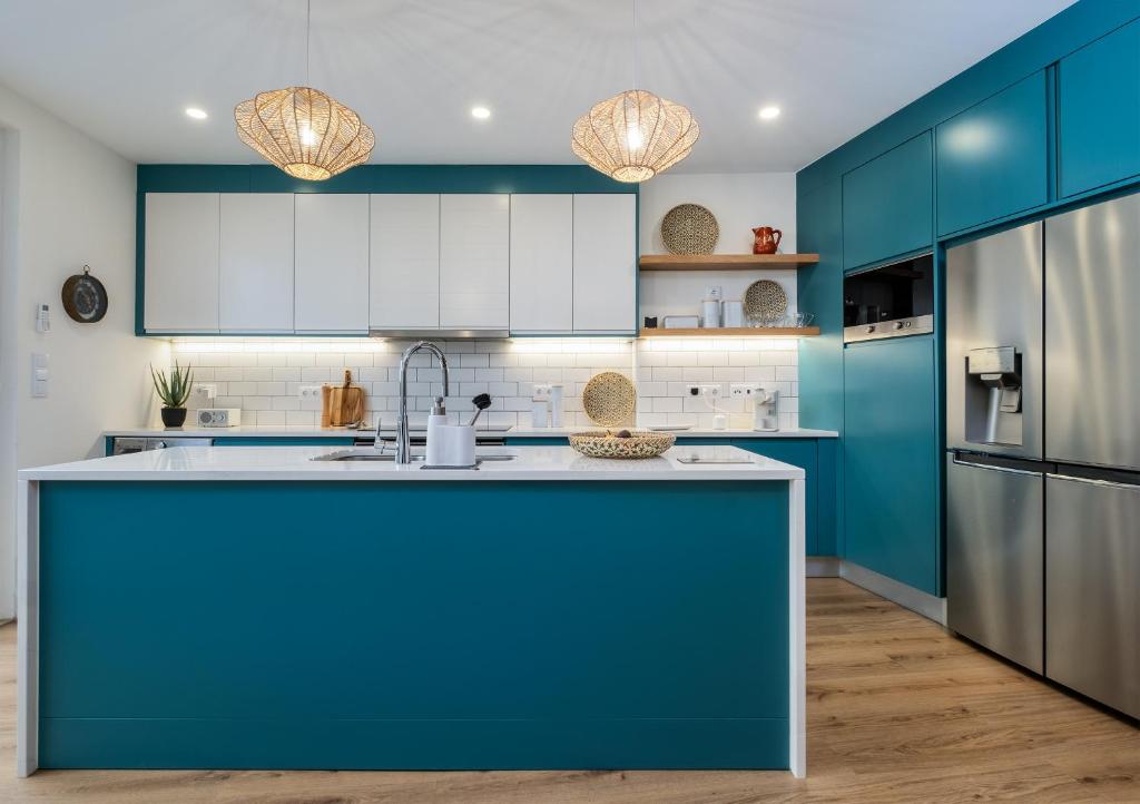 a kitchen with blue cabinets and a refrigerator at Descanso das Palmeiras - HOST & CHILL in Furnas