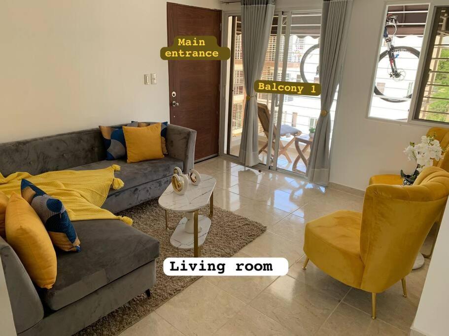 a living room with a gray couch and yellow pillows at Nice and Breezy Apartment in Santiago de los Caballeros