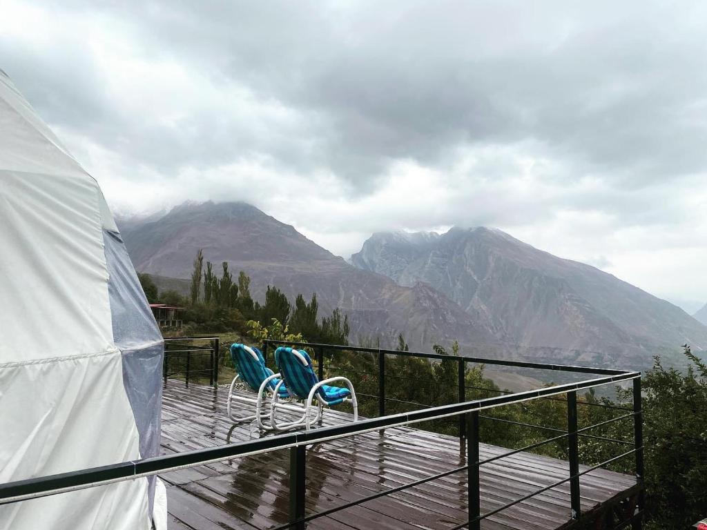 duas cadeiras num deque com montanhas ao fundo em Glamping Resort Hunza em Hunza