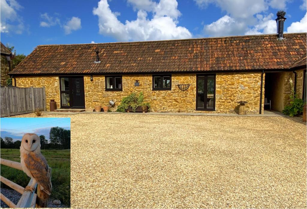 una casa de piedra con un búho sentado en una valla en The Udderhouse - Udderly Unforgettable Retreat, en Donyatt