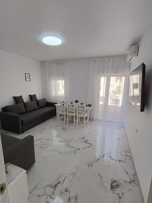 a white living room with a table and a couch at Nuevo apartamento cerca del mar in Denia