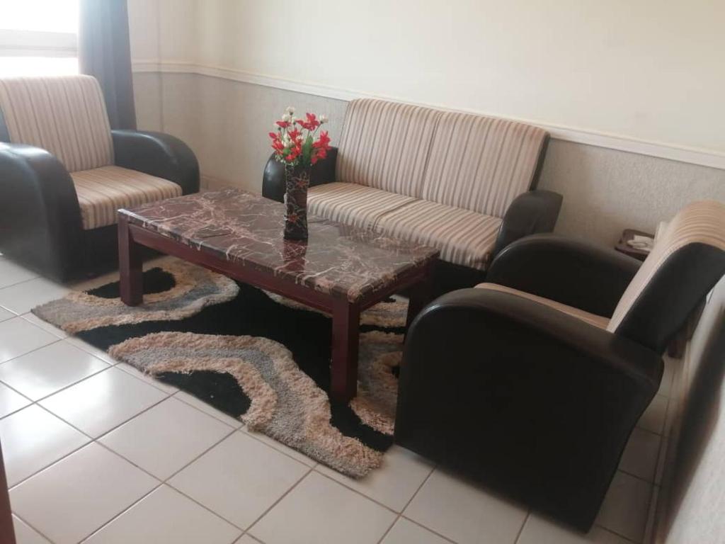 a living room with a coffee table and chairs at Adamaoua Hôtel Plus in Ngaoundéré