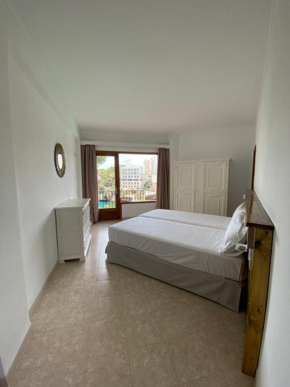 a bedroom with a bed and a large window at Hostal Palmaria in Cala Santanyi