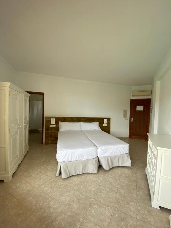 a bedroom with a large white bed in it at Hostal Palmaria in Cala Santanyi