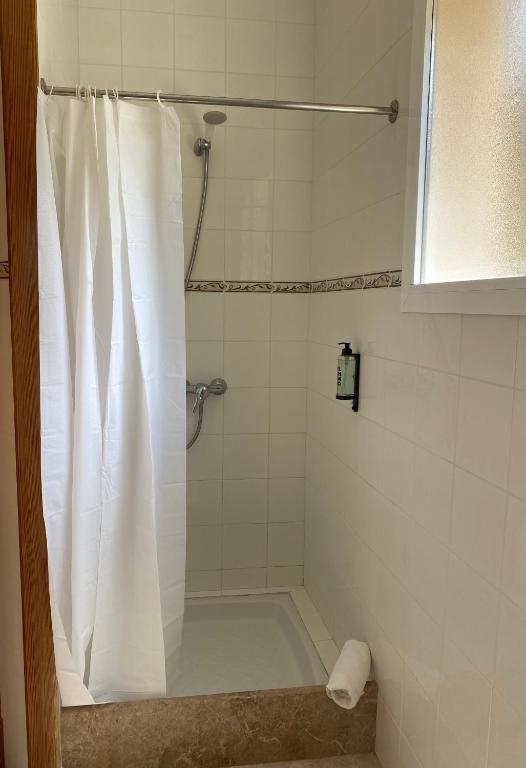 a bathroom with a shower with a white shower curtain at Hostal Palmaria in Cala Santanyi