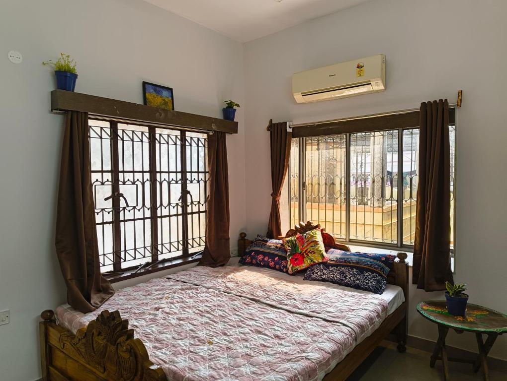 a bedroom with a bed and two large windows at Calcutta Backpackers in Kolkata