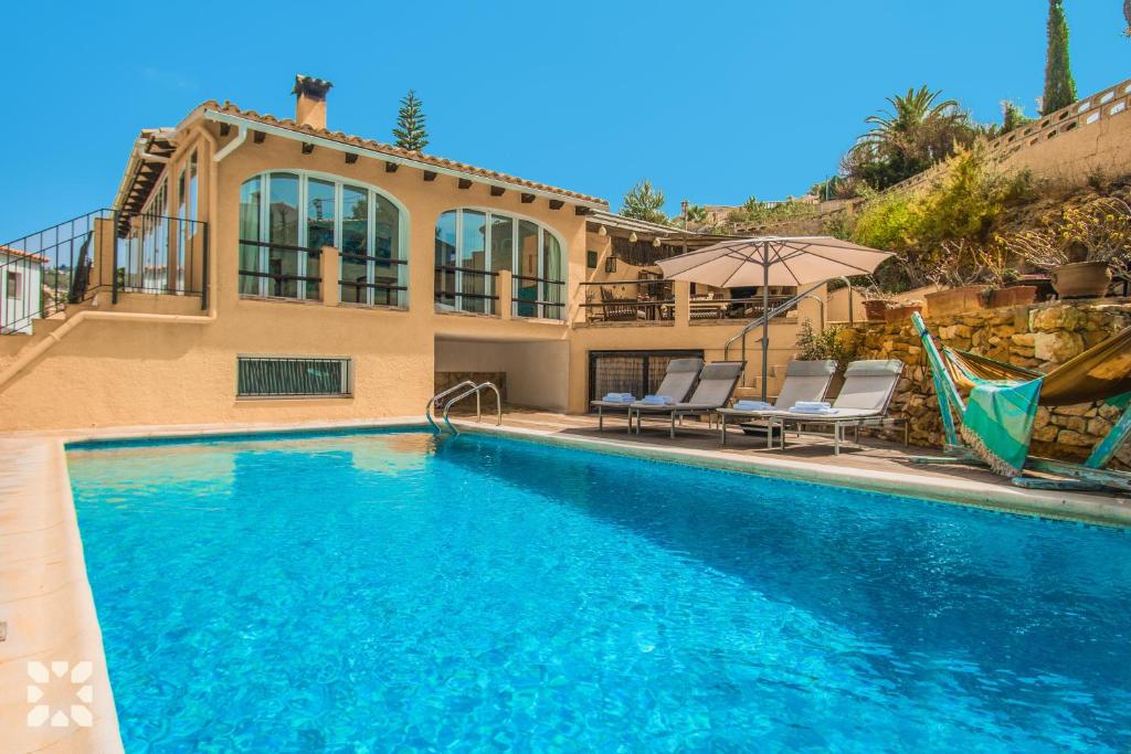 a swimming pool with chairs and a house at Villa Paradise by Abahana Villas in Calpe