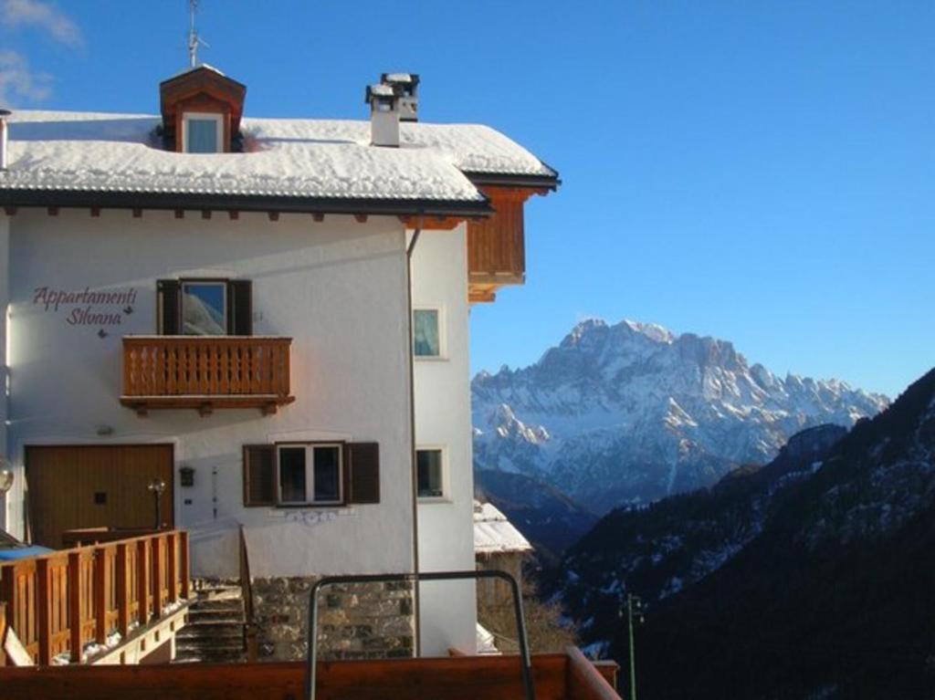 a building with a balcony with mountains in the background at Appartamenti Silvana in Livinallongo del Col di Lana
