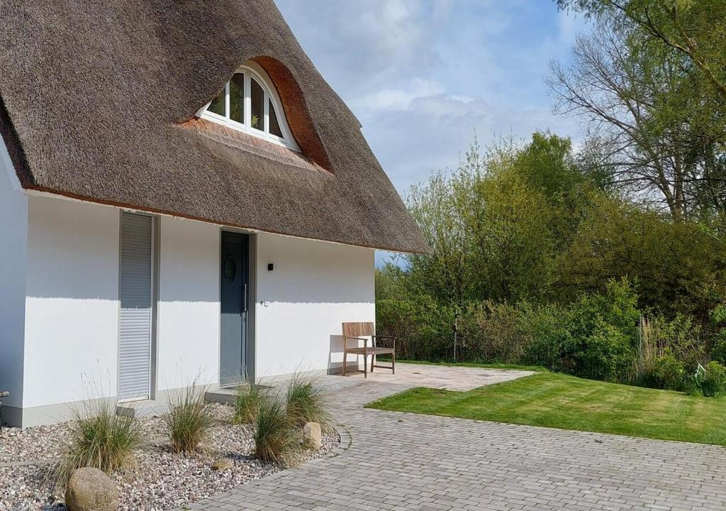 uma casa com um telhado de palha com um banco num quintal em Kleine Binsenjungfer - Ferienhaus mit Sauna und Kamin für 6 Personen em Pepelow