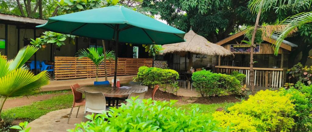 a table and chairs with a green umbrella in a garden at Kafka Gardens in Kisumu