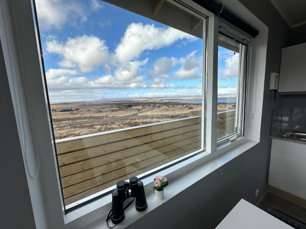 - une fenêtre dans une cuisine avec vue sur un champ dans l'établissement Cabin in Faukás, west part of Iceland - Birta Rentals, à Fossatún