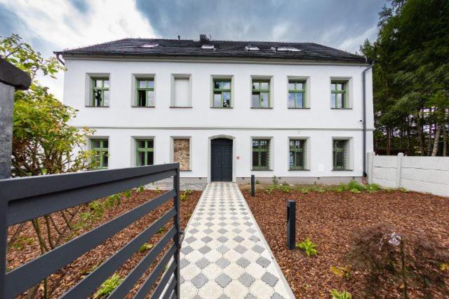 希維德尼察的住宿－Pastorówka，一间白色的房子,设有黑色的门和栅栏