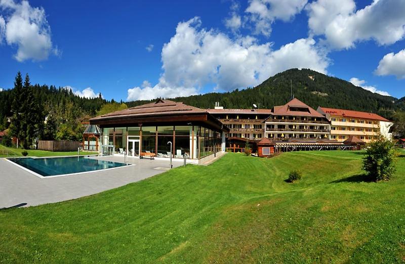 a large building with a swimming pool in the grass at OptimaMed Gesundheitsresort Weißbriach GmbH in Weissbriach