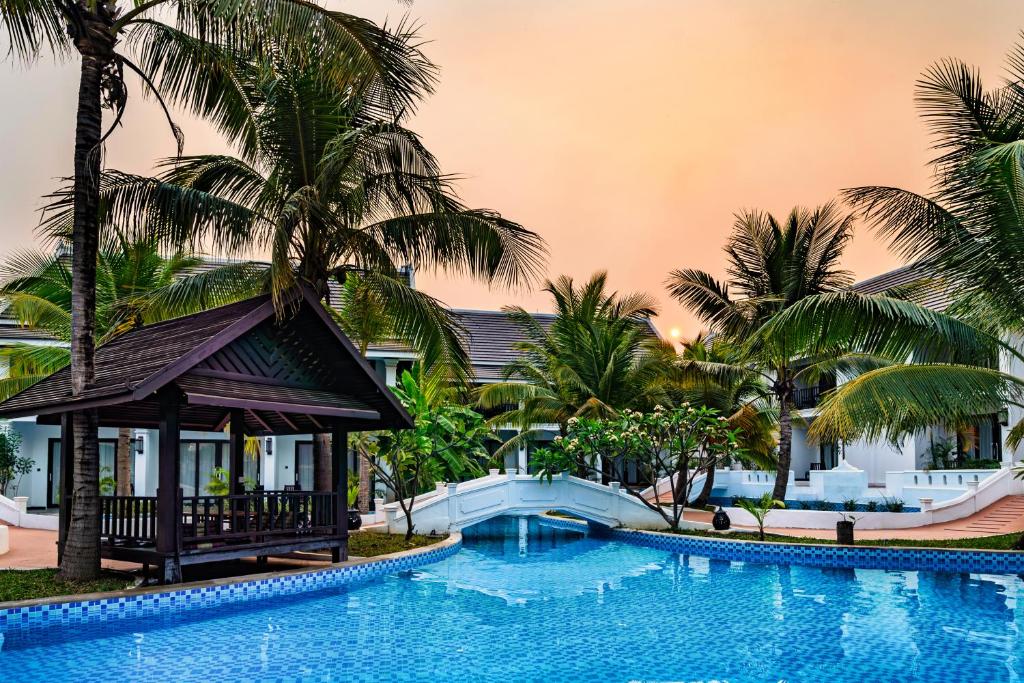 a swimming pool in front of a resort with palm trees at Manyo Hotel and Resort in Luang Prabang
