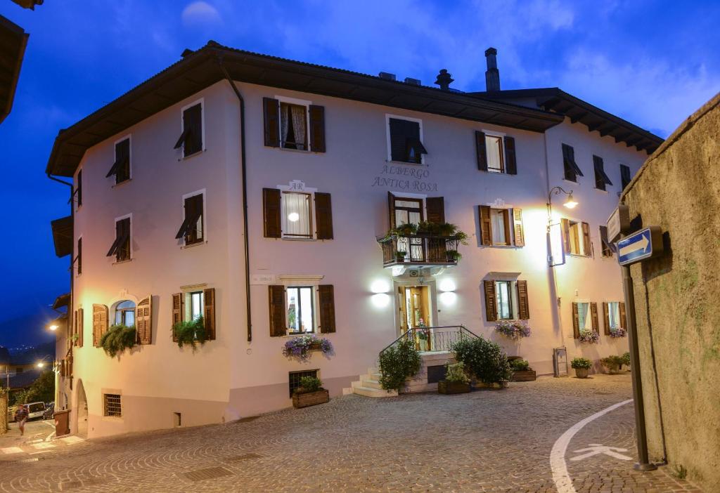 Un grand bâtiment blanc avec des plantes sur les fenêtres dans l'établissement Albergo Antica Rosa, à Levico Terme