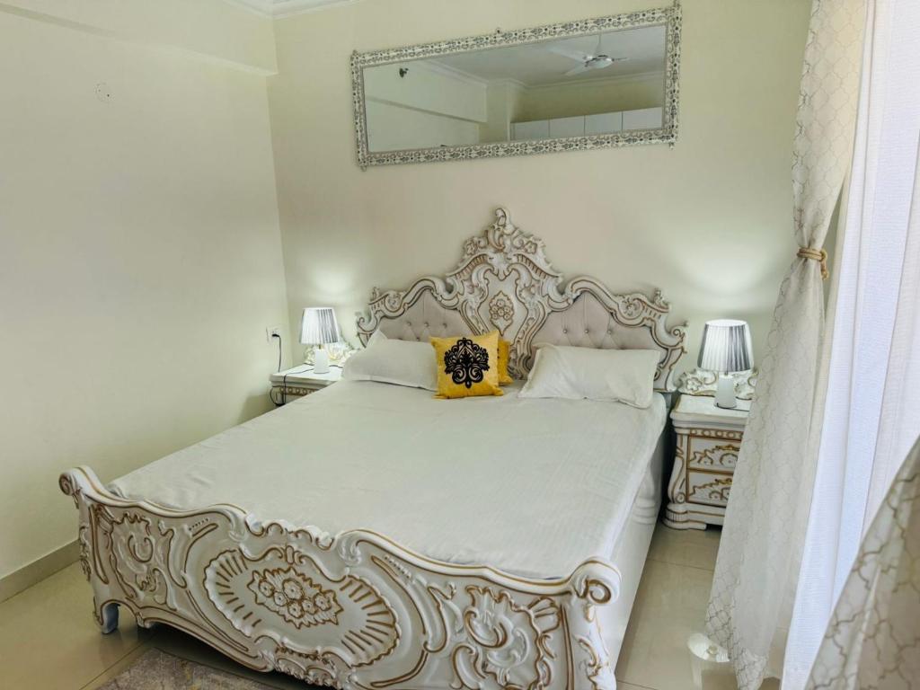 a bedroom with a white bed with a mirror on the wall at Downtown haven in Mohali