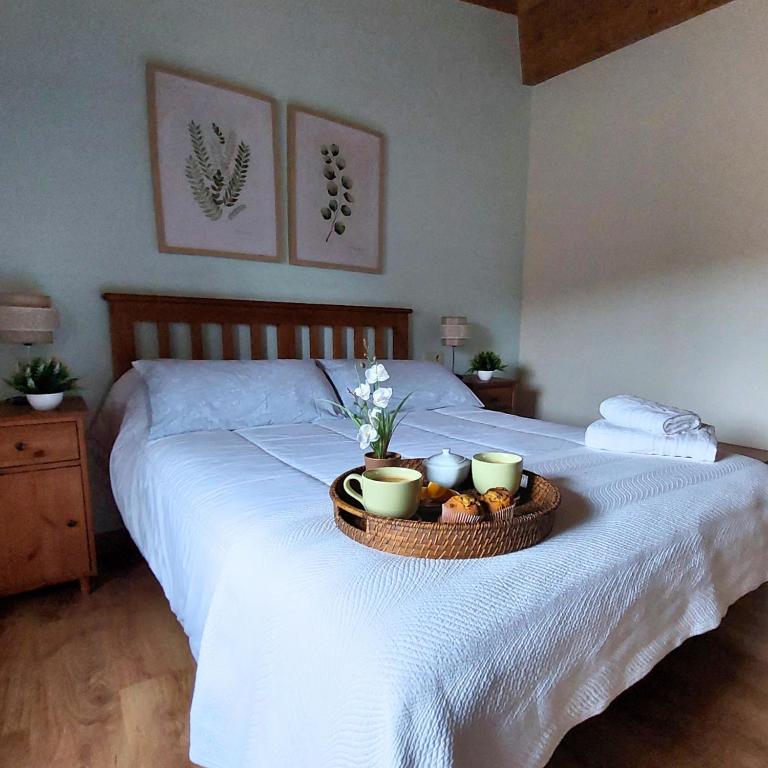 a bed with a tray of food and cups on it at El Lagar del Abuelo en los Arribes del Duero, Badilla, Zamora in Zamora