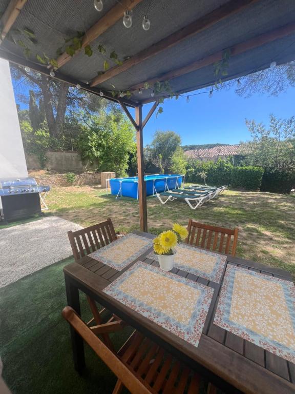 a wooden table with two chairs and a table with flowers on it at Apartamento loft, jardín y piscina privada in Romanyá de la Selva