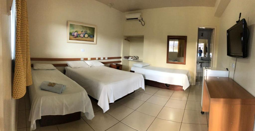 a hotel room with two beds and a television at Hotel Master Cuiabá in Cuiabá