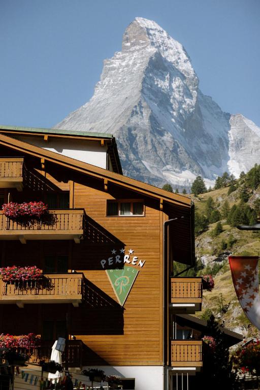 a building with a snow covered mountain in the background at Alpine Hotel Perren in Zermatt