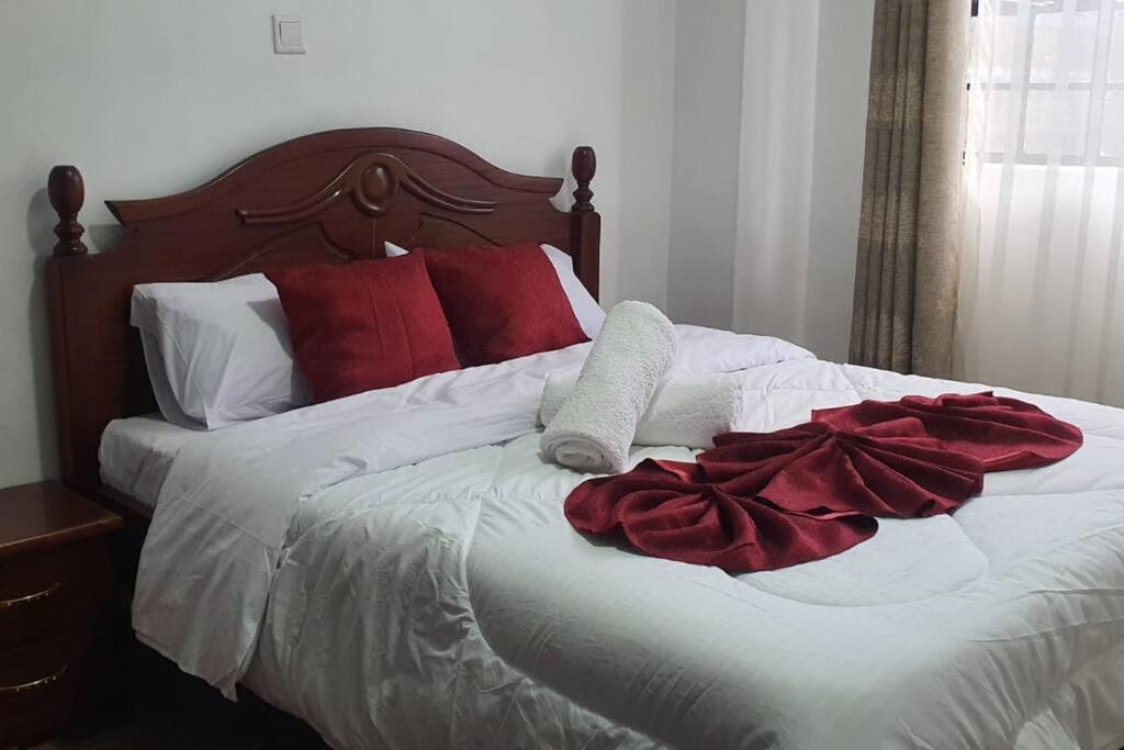 uma cama branca com almofadas vermelhas e brancas em VillaRoma's Urban Retreat A Stylish Warm Loft em Eldoret